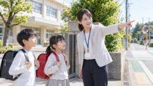 学校前の通学路で、先生と子どもたちが安全な避難方向を確認している様子
